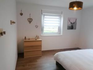 ein Schlafzimmer mit einem Bett, einem Fenster und einer Kommode in der Unterkunft La Perle d'Alsace in Bernardswiller