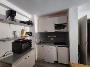 una piccola cucina con armadietti bianchi e forno a microonde di Appartement Plagne 1800, 2 pièces, 4 personnes - FR-1-181-2708 a La Plagne Tarentaise