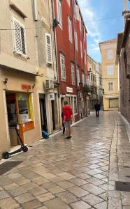 a person walking down a cobblestone street with buildings at NEW!Beautiful modern bedrooms and apt Old town Zadar- Great location in Zadar