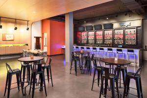 a restaurant with tables and chairs and a bar at Aloft Seattle Sea-Tac Airport in SeaTac