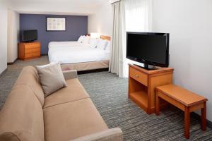 a hotel room with a couch and a tv and a bed at Residence Inn Lexington North in Lexington