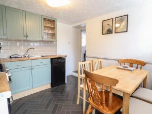 a kitchen with blue cabinets and a wooden table at Gamekeepers Cottage in Conwy