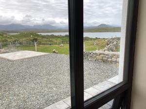 a window with a view of a field and a rock wall at Apartment at Island Cottage, Inishnee, Roundstone in Galway