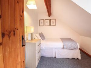 a bedroom with a bed and a dresser in a attic at Oak Cottage in Conwy