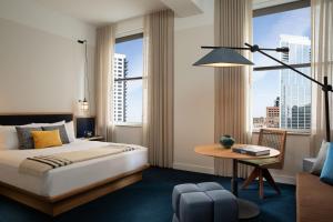 a hotel room with a bed and a desk and windows at Emery Hotel, Autograph Collection in Minneapolis