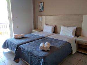 two beds in a hotel room with towels on them at Delfini in Nydri