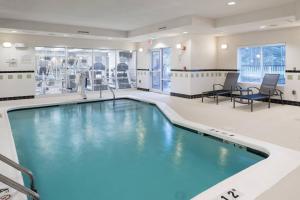 オーバーランド・パークにあるFairfield Inn & Suites Kansas City Overland Parkのチェア付きの広い客室に青い水のプールがあります。