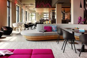 a room with a couch and tables and chairs at Moxy Munich Airport in Oberding