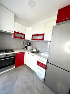 uma cozinha com armários vermelhos e brancos e um frigorífico em Apartman Solin 1, parking em Solin
