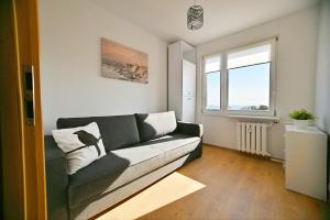 a living room with a green couch and a window at Horyzont by 3City Rentals in Gdynia