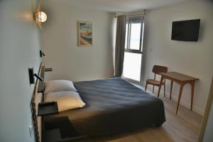 um quarto com uma cama, uma secretária e uma janela em hôtel Le Grand Large em Gruissan