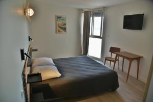 Un dormitorio con una cama con un escritorio y una ventana. en hôtel Le Grand Large, en Gruissan