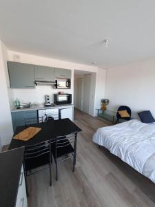 ein Schlafzimmer mit einem Bett und einem Tisch sowie eine Küche in der Unterkunft appartement remblai saint hilaire de riez in Saint-Hilaire-de-Riez