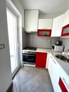 una cocina con armarios rojos y blancos y fregadero en Apartman Solin 1, parking en Solin