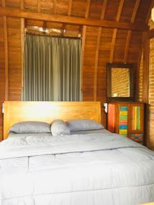 a bedroom with a large bed with a wooden headboard at Kubu Pering in Keramas