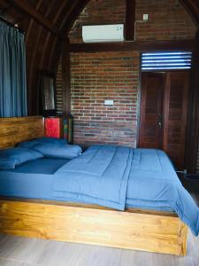 a wooden bed in a room with a brick wall at Kubu Pering in Keramas