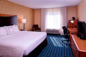 Fairfield Inn and Suites New Buffalo في نيو بافالو: غرفة فندقية فيها سرير ومكتب وتلفزيون