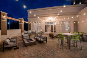 eine Terrasse mit Tischen, Stühlen und Lichtern in der Nacht in der Unterkunft Courtyard by Marriott Raleigh Cary/Parkside Town Commons in Cary