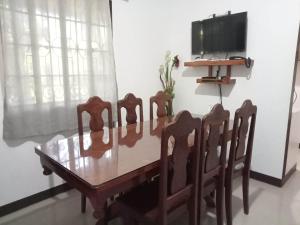 a dining room table with four chairs and a television at Dos Casa Guest House in Puerto Princesa City +7 photos