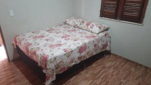 uma pequena cama num quarto com uma colcha floral em Sua Casa em Flecheiras em Flecheiras