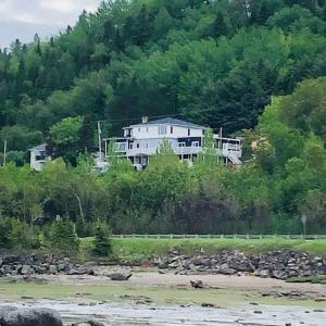 uma grande casa branca no lado de uma colina em Suite 2, Flèche du fjord, vue Saguenay, Mont Valin em Saint-Fulgence