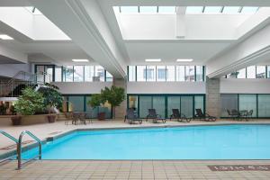 une piscine dans le therium d'un immeuble avec des tables et des chaises dans l'établissement Halifax Marriott Harbourfront Hotel, à Halifax