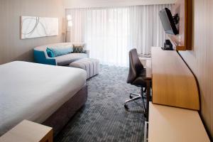um quarto de hotel com uma cama, um sofá e uma televisão em Courtyard by Marriott Richmond Airport em Sandston