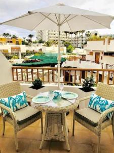 una mesa y sillas con una sombrilla en el balcón en Costa Adeje Modern Studio, close to the beach en Adeje