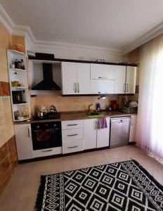 a kitchen with white cabinets and a black and white rug at My Home in Beysehir