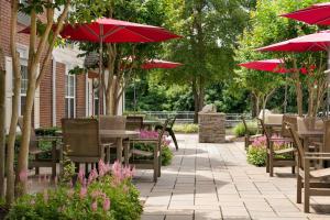 un patio con mesas y sillas y sombrillas rojas en TownePlace Suites Gaithersburg, en Gaithersburg