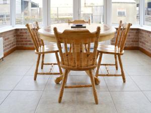 una mesa de madera y sillas en una habitación con ventanas en Stable Cottage 3 - Ukc3742, en Bawdeswell