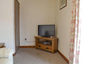 a television sitting on a wooden stand in a room at Stable Cottage 3 - Ukc3742 in Bawdeswell
