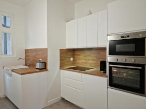 a kitchen with white cabinets and a stove top oven at Le Ness - Face au Pont des Amours - Majord'Home in Annecy