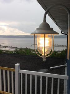 a lamp hanging over a white fence with a view of the ocean at Séjour, Flèche du fjord, vue Saguenay, Mont Valin in Saint-Fulgence