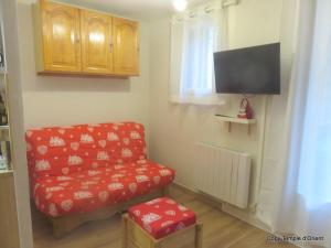 a living room with a red chair and a tv at ALLOS village STUDIO cosy avec balcon in Allos