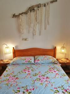 a bed with a blue comforter and two lamps at Caseta de pescadors a les cales de Colera, 2ª linea de mar in Colera