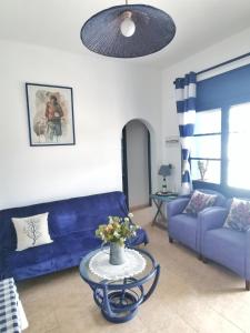 a living room with a blue couch and a table at Caseta de pescadors a les cales de Colera, 2ª linea de mar in Colera