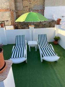 two chairs and a green umbrella on a patio at Casa Alora in Alora