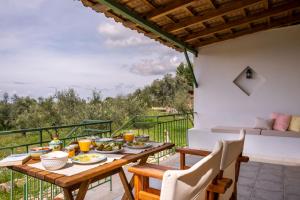 a table with food and drinks on the balcony of a house at Chamaloni Cottages in Finikounta