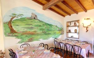 a dining room with tables and chairs with a painting on the wall at La Tankitta Turismo Rurale in Stintino +16 photos