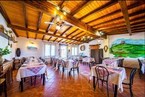 una sala da pranzo con tavoli, sedie e un dipinto di La Tankitta Turismo Rurale a Stintino