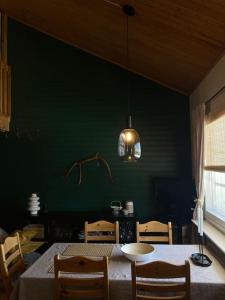ein Esszimmer mit einem Tisch, Stühlen und einer grünen Wand in der Unterkunft One-bedroom apartment in the center of Saariselkä in Saariselkä