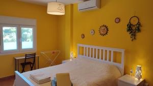 - une chambre avec un lit blanc et des murs jaunes dans l'établissement B&B Casa El Corasueño, à Almogía