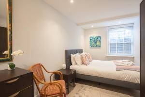 een slaapkamer met een bed, een stoel en een raam bij Spacious 2BR Victorian Cheltenham flat in Cotswolds Sleeps 6 - FREE Parking in Cheltenham