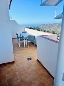 Cette chambre dispose d'un balcon avec une table et des chaises. dans l'établissement Ático con increíbles vistas a las montañas y mar, à Frigiliana