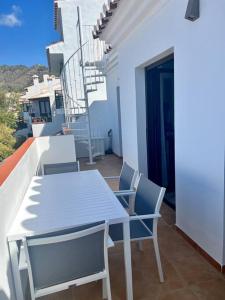 d'une table et de chaises blanches sur un balcon. dans l'établissement Ático con increíbles vistas a las montañas y mar, à Frigiliana