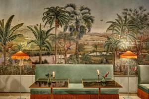 a living room with a green couch and a mural of palm trees at Palazzo Vecchio Taormina in Taormina