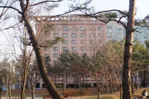 un gran edificio con un montón de árboles delante de él en Aura Hotel en Ansan