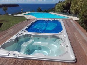 Chambre d'hotes "Villa Rayon Vert" في ديساي: حوض استحمام ساخن على سطح السفينة بجوار حمام سباحة
