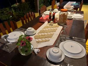 una mesa con platos blancos y un jarrón de flores. en K2 Lembeh Dive Resort en Bitung